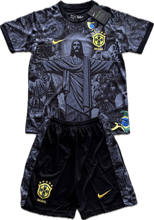 Load image into Gallery viewer, Youth soccer jersey set featuring a black design with the Christ the Redeemer statue and Brazilian cultural elements, with the Nike logo and gold accents.
