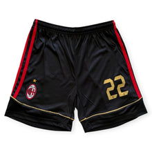 Load image into Gallery viewer, Black AC Milan soccer shorts with red side stripes, a red and black club crest on the left leg, and the number 22 in gold on the right leg.
