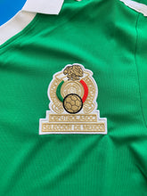 Load image into Gallery viewer, "Mexico 1986 World Cup Jersey Close-Up Detail - Adidas Retro Soccer Kit with Official El Tri Badge, Premium Green Fabric, and Authentic World Cup Design Elements" Chest embroidered logo mexico