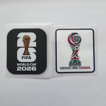 Load image into Gallery viewer, Two FIFA World Cup 2026 emblems or stickers shown side by side on a plain light background. The left piece is black with a large white '26' and the gold trophy graphic, plus 'FIFA' and 'WORLD CUP 2026' text.
