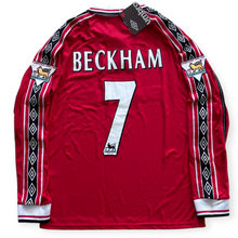 Load image into Gallery viewer, A red long-sleeve Manchester United football jersey shown from the back, featuring 'BECKHAM' and the number '7' in white. The sleeves have black and white diamond-patterned stripes, and the jersey has Umbro and Manchester United patches.
