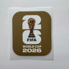 Load image into Gallery viewer, A square sticker featuring the FIFA World Cup 2026 logo, with a gold and white design on a white backing card, photographed against a light gray background.
